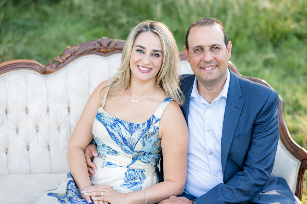 Mom and Dad seated on a couch in a field in family photo session at West 12 Ranch with Gia Chong Photography, Lodi CA photographer