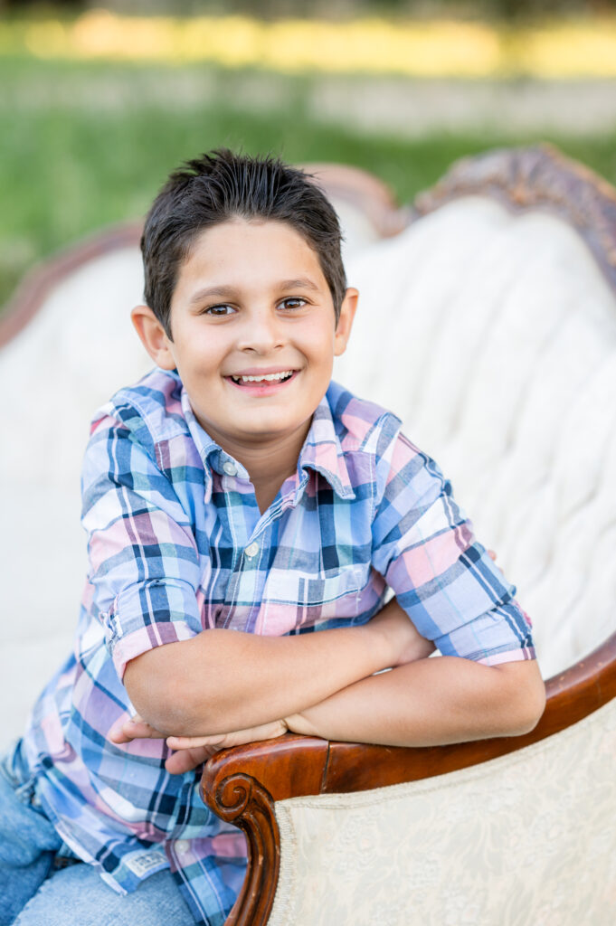 Little boy seated on a couch in a field in family photo shoot at West 12 Ranch with Gia Chong Photography, Lodi CA photographer