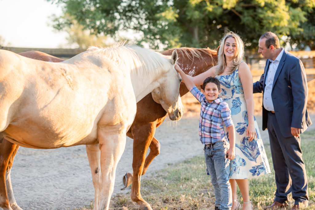 Family of three petting horses during their shoot at West 12 Ranch with Gia Chong Photography, Lodi CA photographer