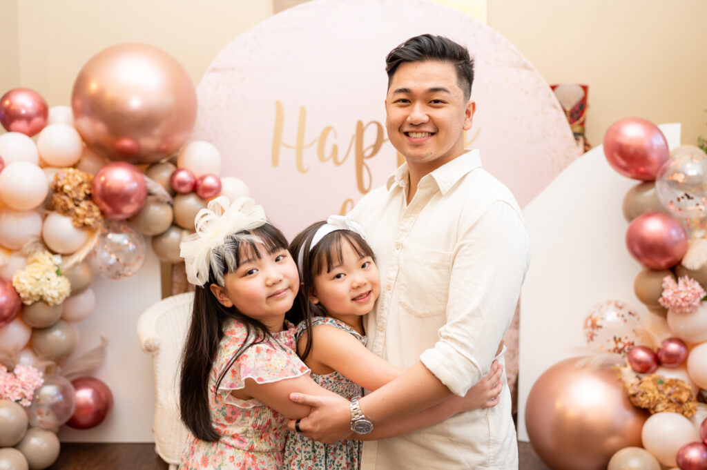 Brother and sisters posing in a balloon decorated room during a birthday party photographed by Gia Chong Photography in Stockton, California.