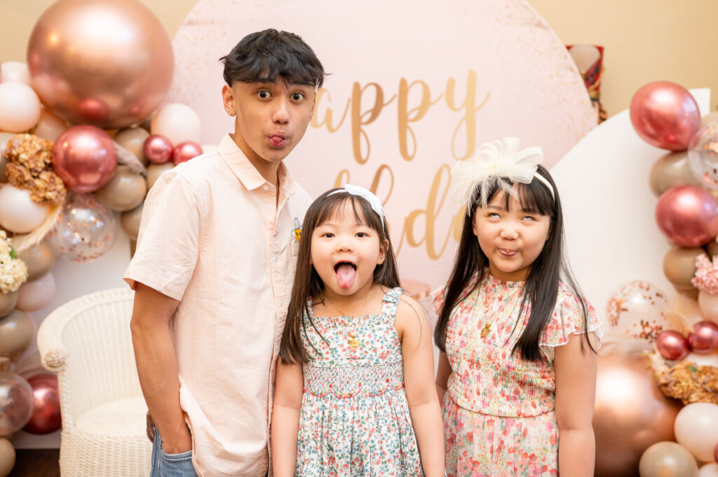 Brother and sisters posing in a balloon decorated room during a birthday party photographed by Gia Chong Photography in Stockton, California.