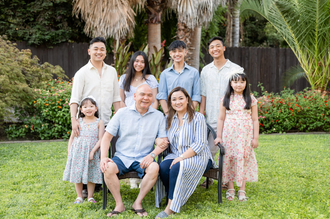 Mom and Dad seated with kids standing during a backyard family session with Gia Chong Photography at Stockton, CA