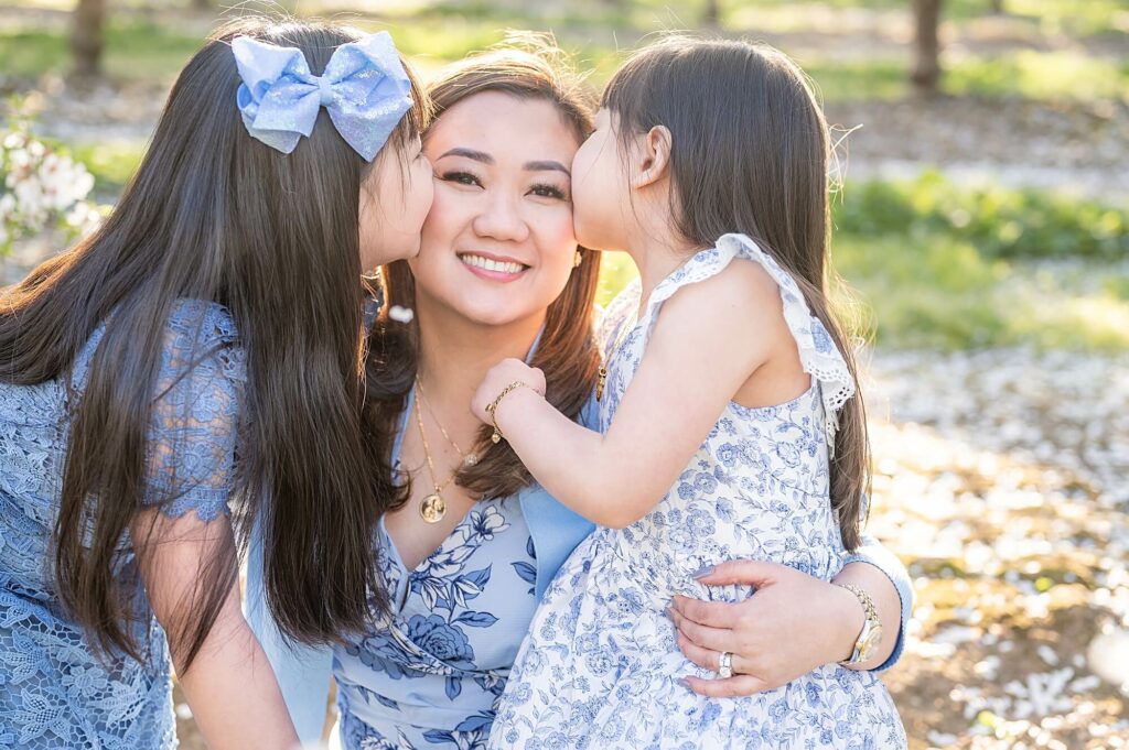 Sisters kissing mom pose idea almond blossoms photo session