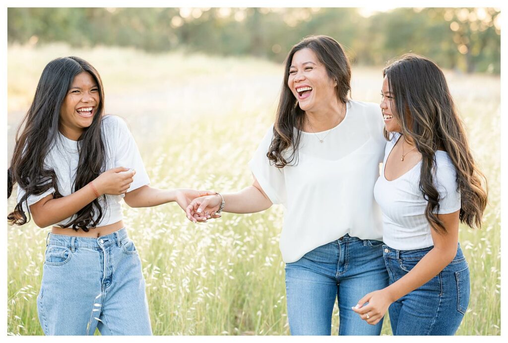 candid laughing moment with mom and daughters during outdoor family photo session