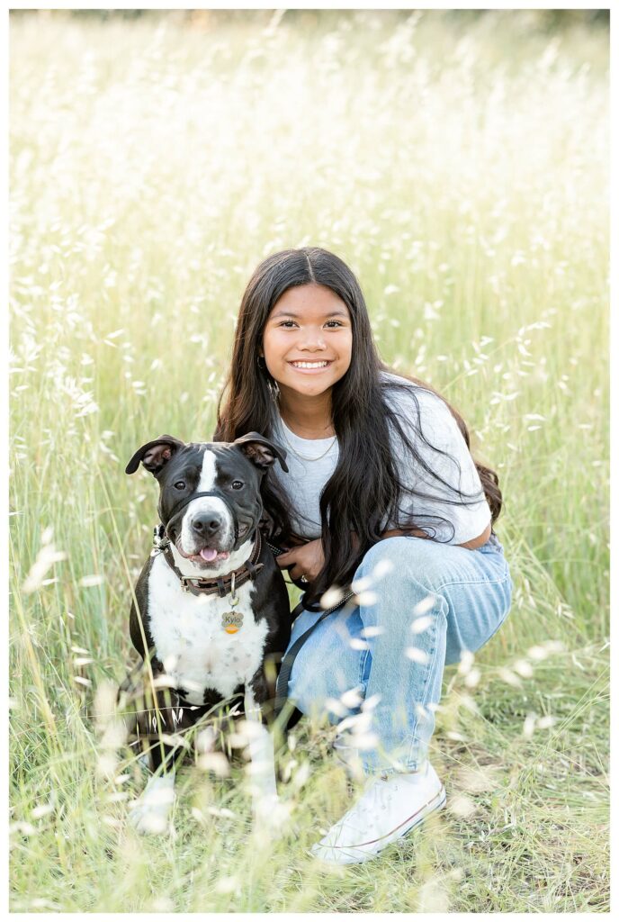 young girl crouched down on the ground with her dog