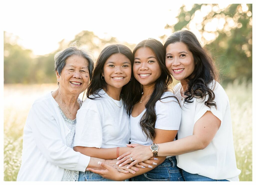 grandmother, mother and daughters hugging and smiling at the camera