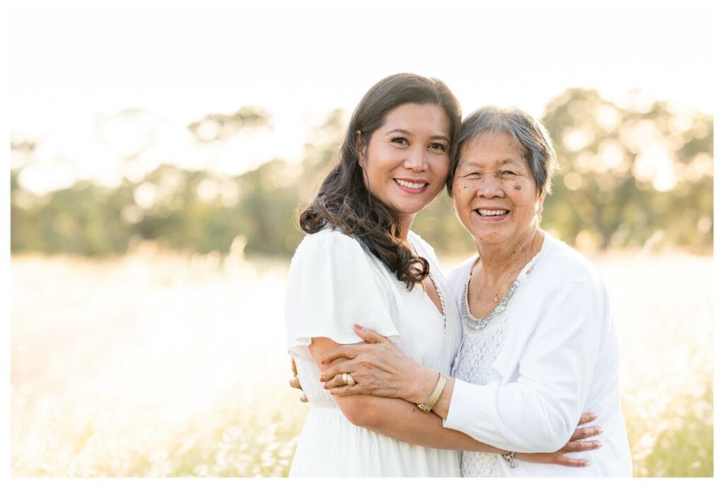 grandmother and mother hugging and smiling at the camera