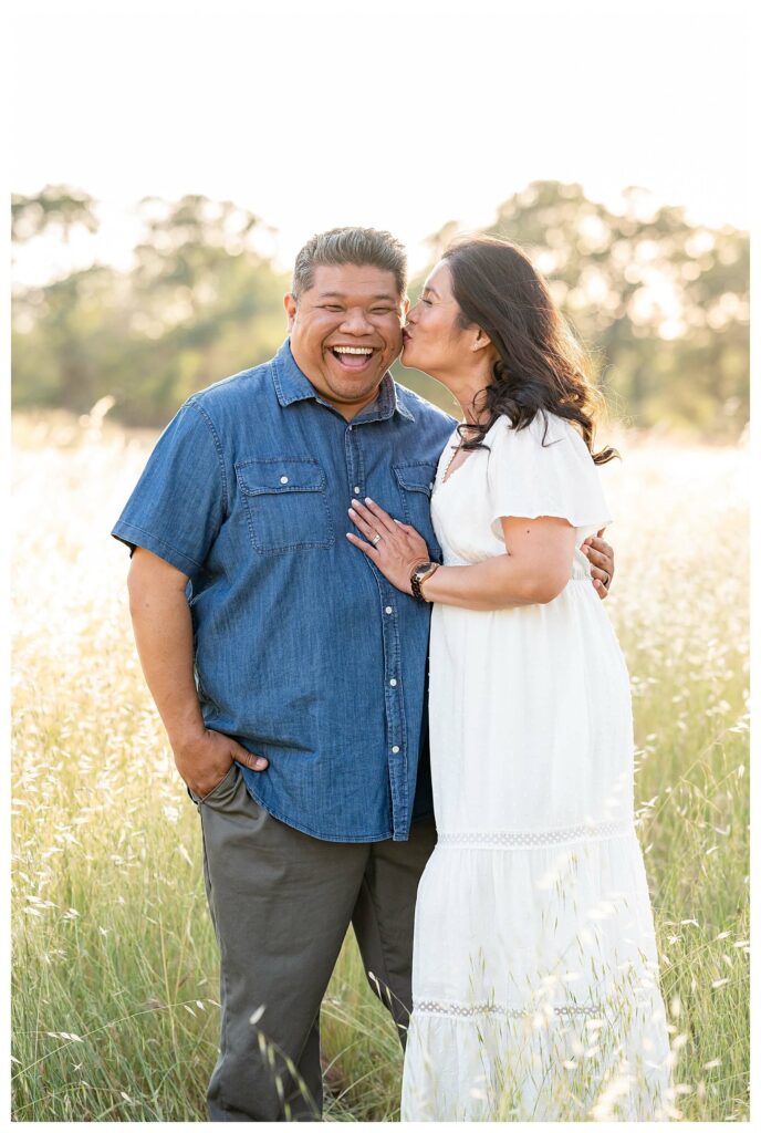 dad laughing at the camera and mom kissing him on the check