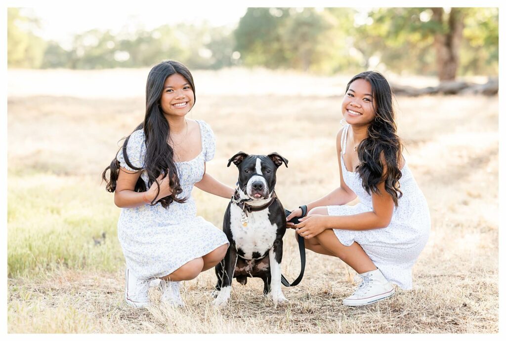 daughters crouched down and posing with family dog
