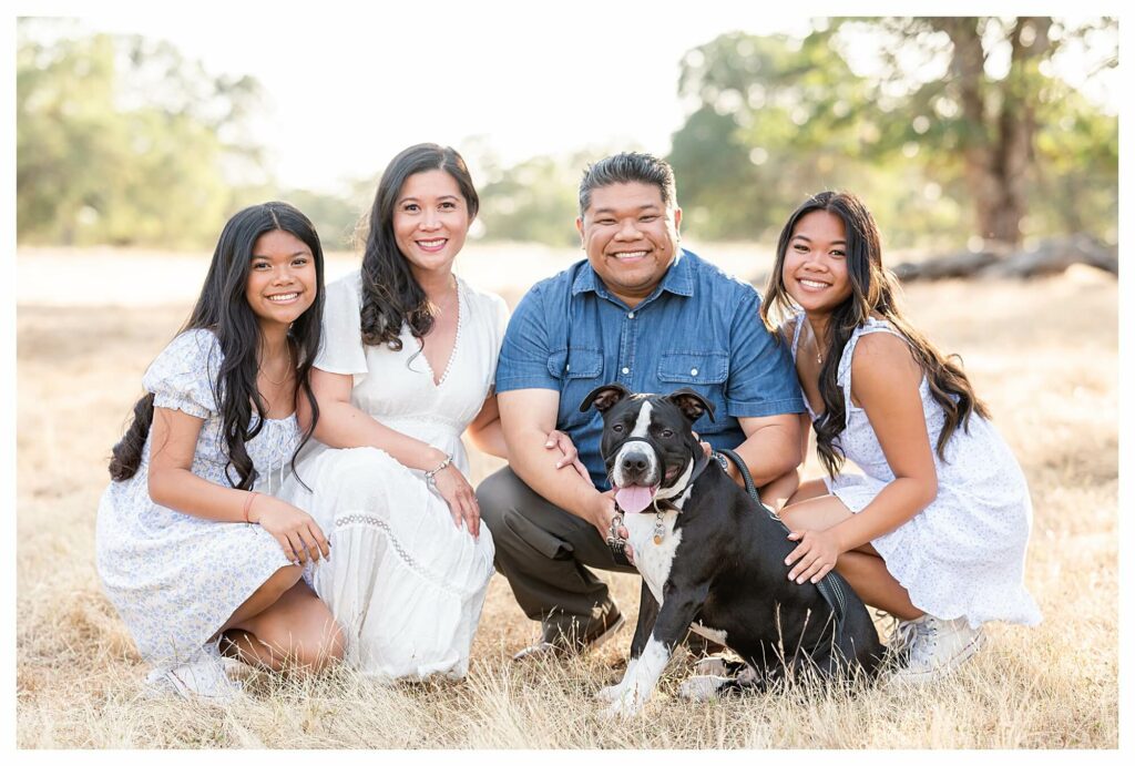 family posing crouched on the ground with family dog