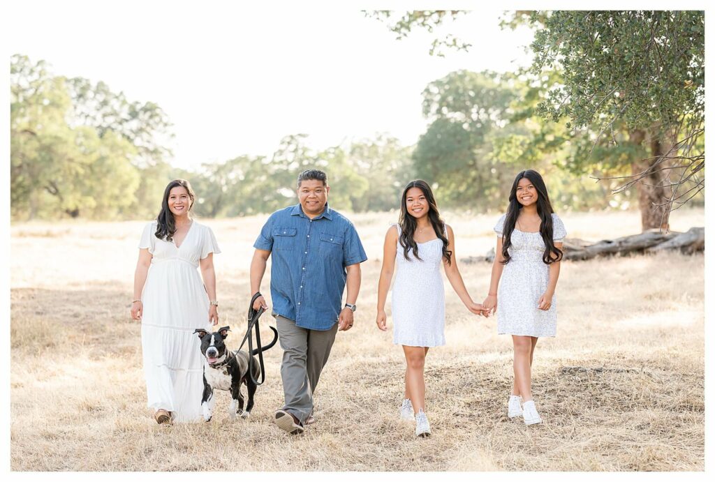 Family walking with their dog in a field during outdoor family photo session Roseville CA