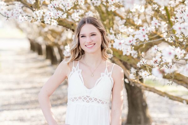 senior girl smiling at the camera during almond blossom photo shoot