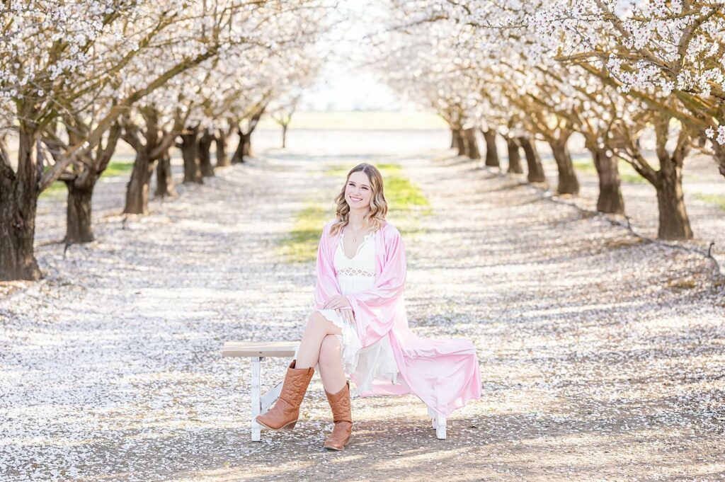 Senior girl with a pink grad gown during her unique almond blossom session