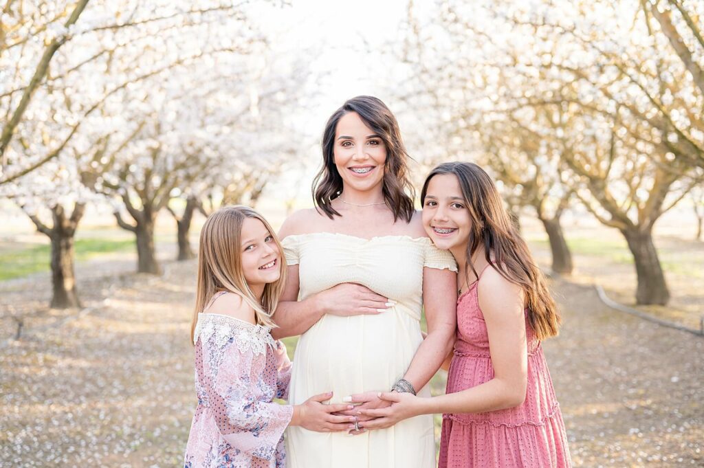 maternity pose with daughters in almond blossom photoshoot