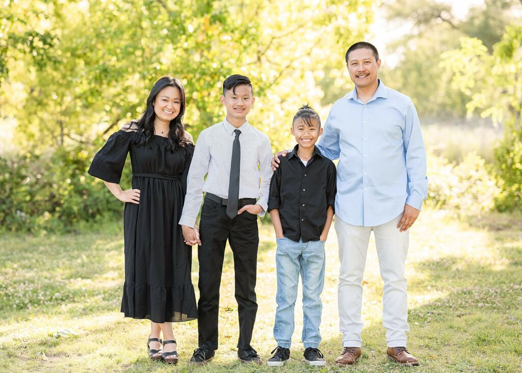 family standing and smiling at the camera during graduation photo session