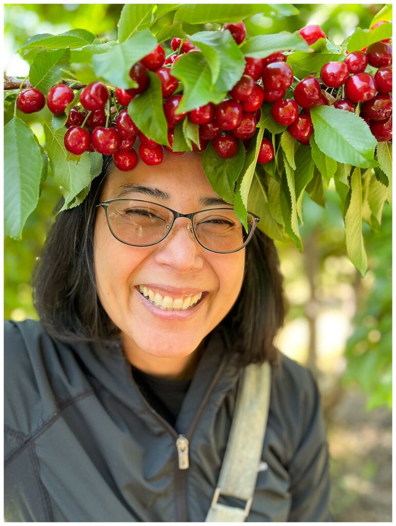 Woman smiling at the camera with a cherry crown in a cherry orchard