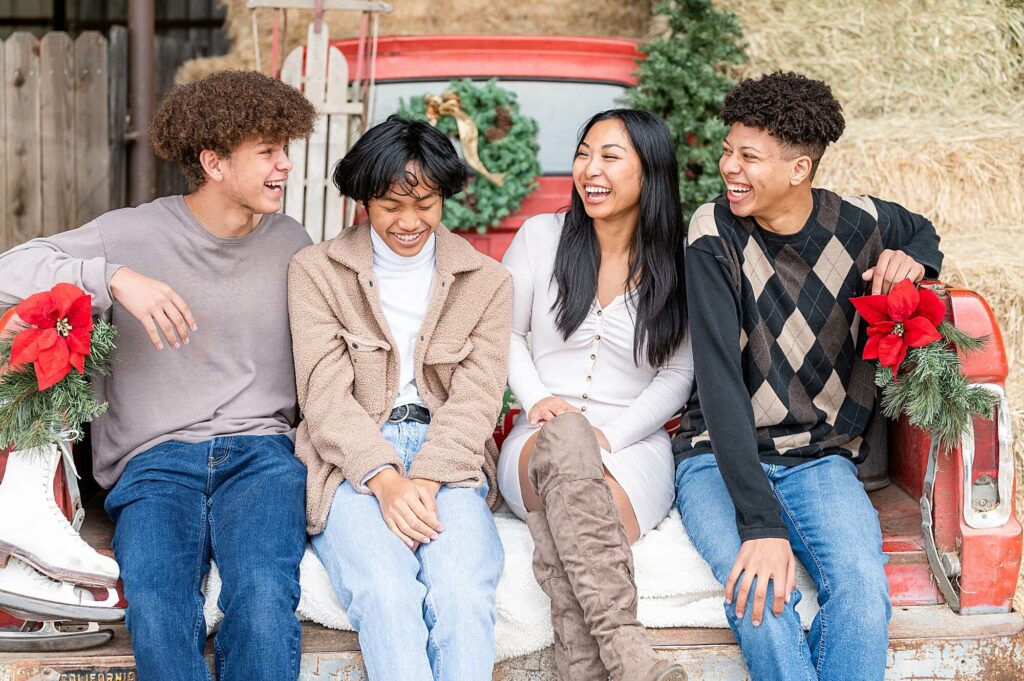 posing idea for teenagers laughing while during red truck christmas mini sessions