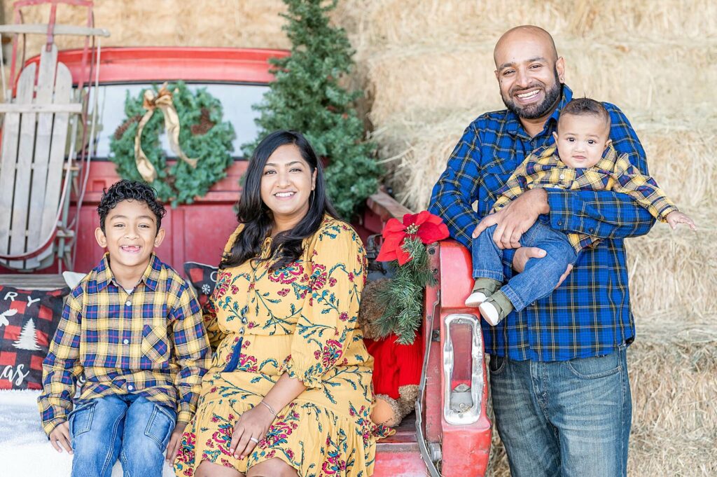 Family of 4 smiling at the camera during a Red Truck Christmas Mini Session