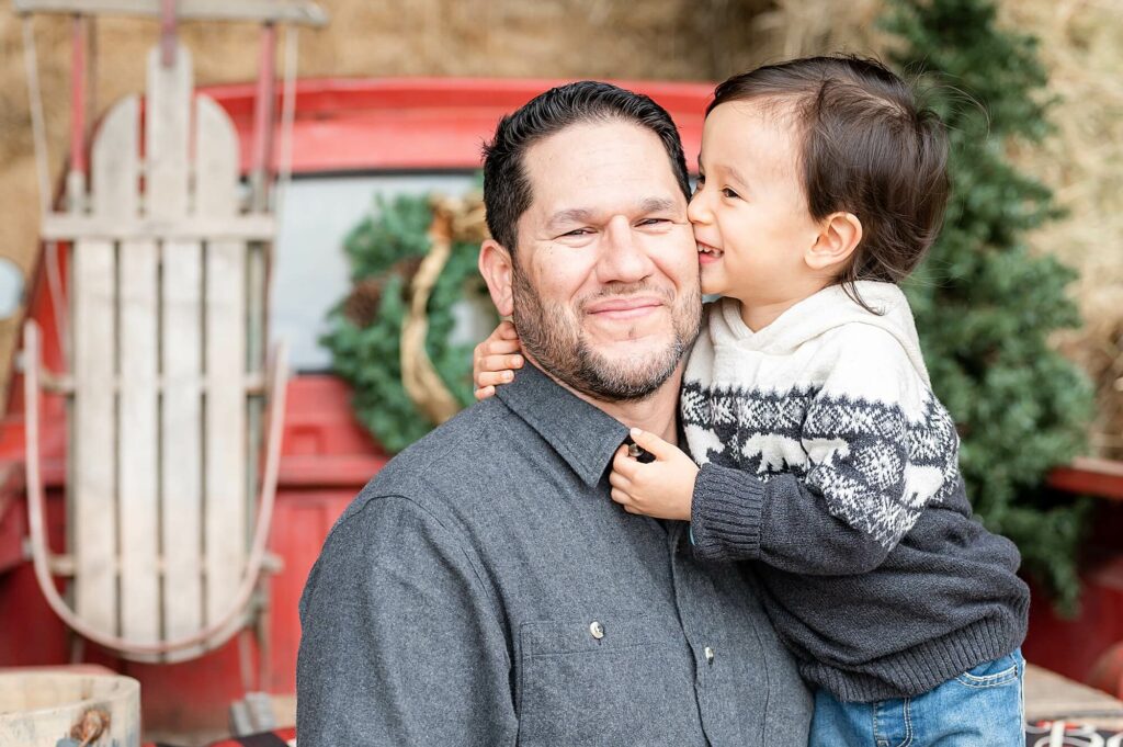 Mini Session posing idea Dad smiling at the camera and his son kissing him