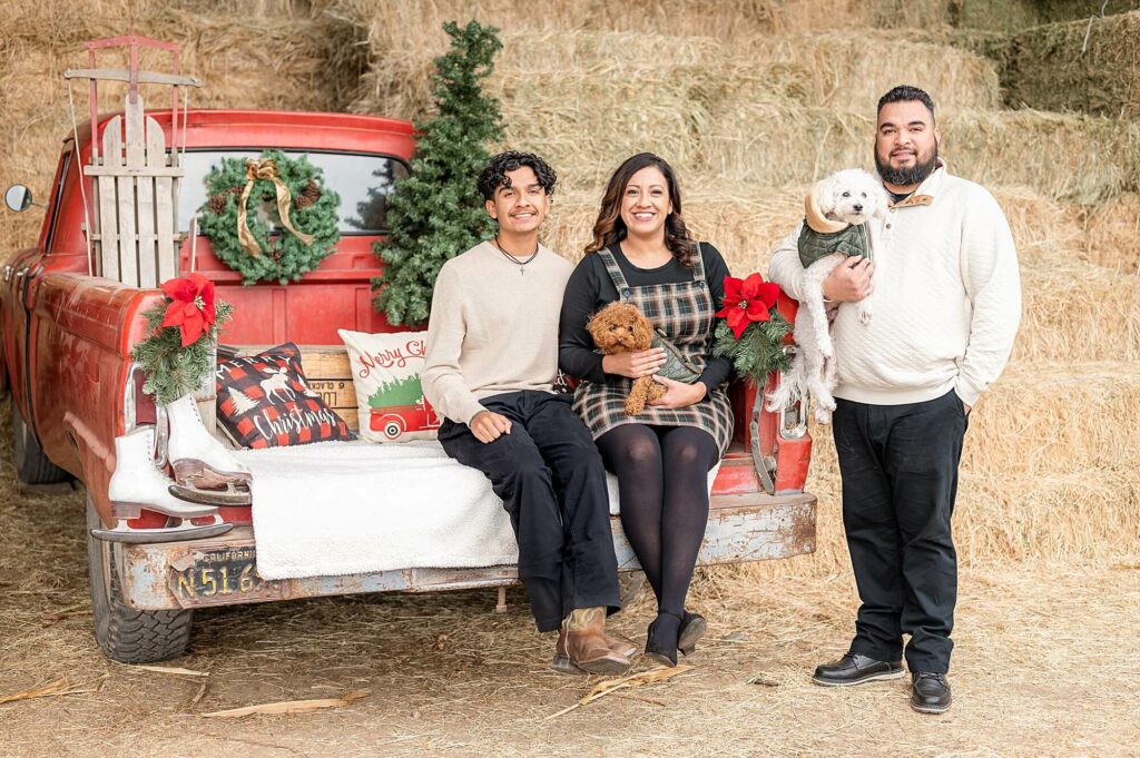 Family looking at the camera with their dogs seated on a red truck