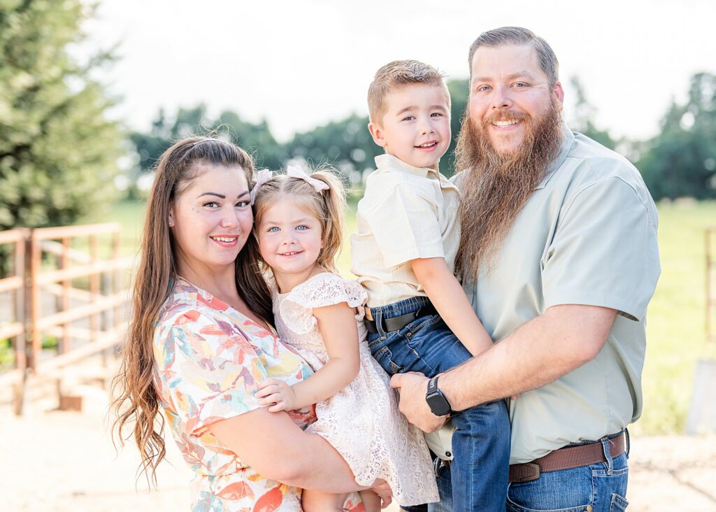 Family hugging and smiling at the camera during a family photo session at Champaign Ranch in Herald CA