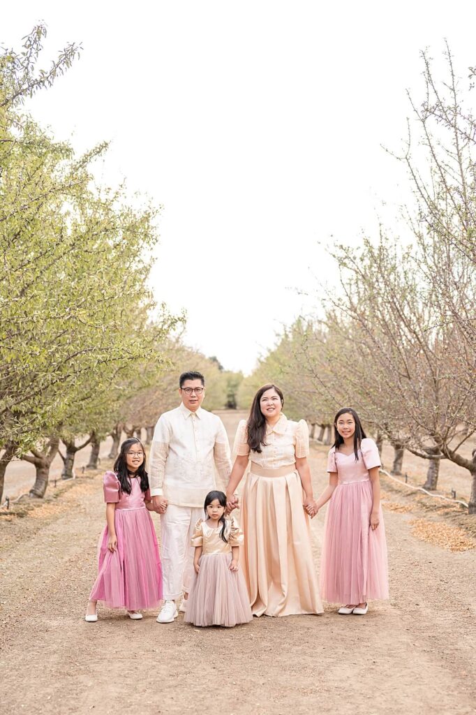 Family of 5 smiling at the camera in an almond orchard in Golden R Ranch Stockton CA