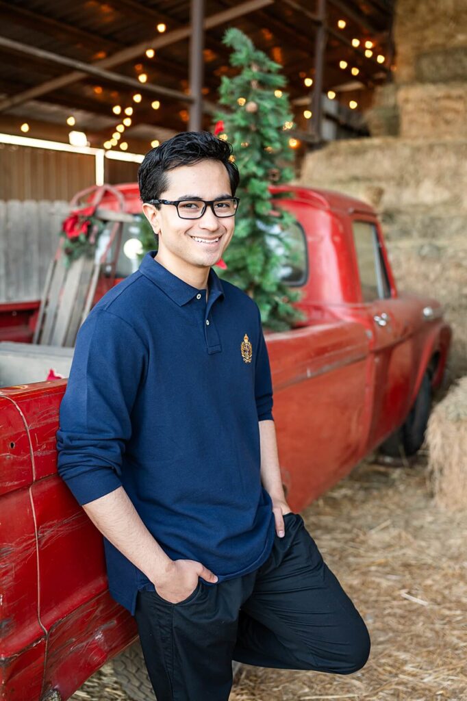 Young man leaning against a red truck at West 12 Ranch Lodi