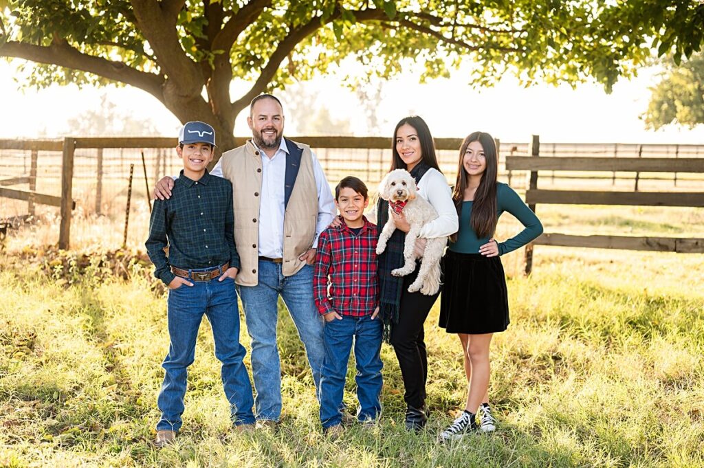 Family with a dog smiling at the camera in a field at West 12 Ranch Lodi