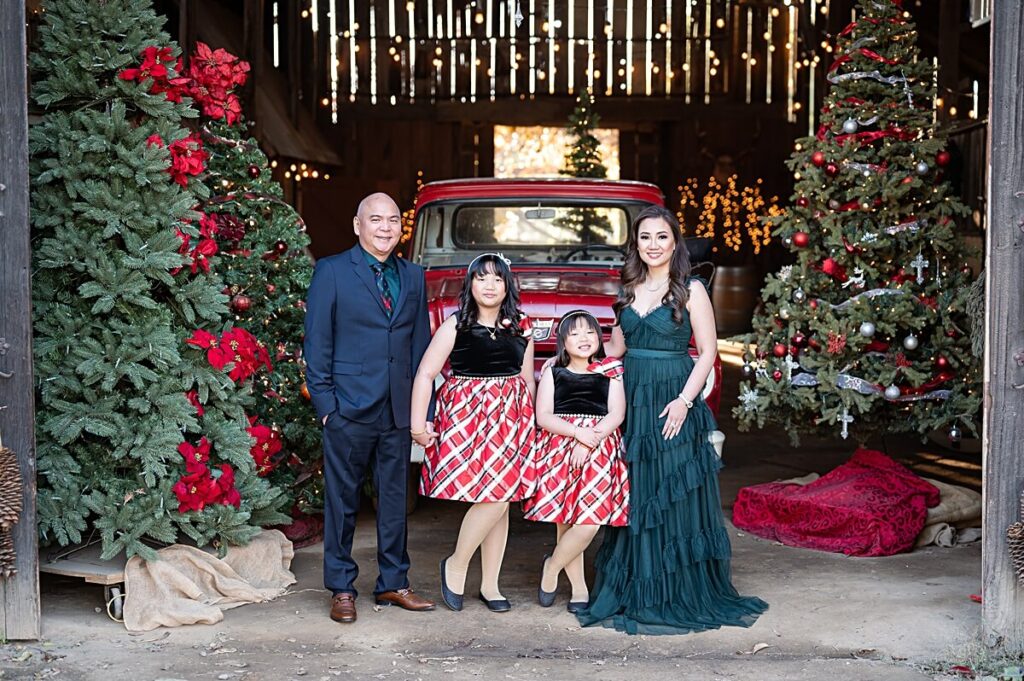 Family of four smiling in front of West 12 Ranch Christmas Barn