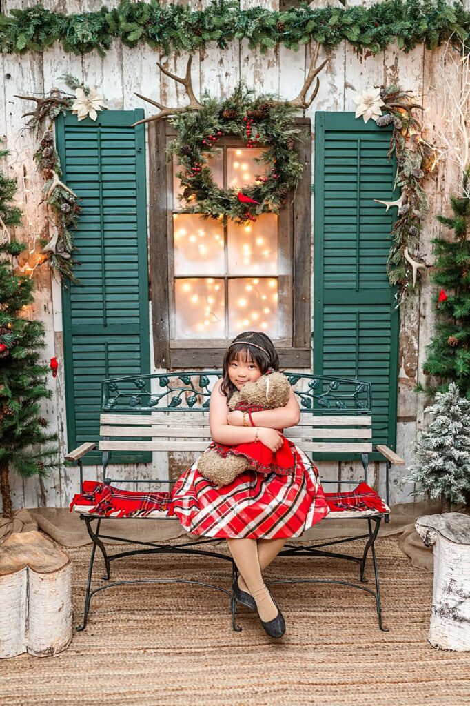 Little girl hugging a teddy bear at a holiday set up in West 12 Ranch Lodi