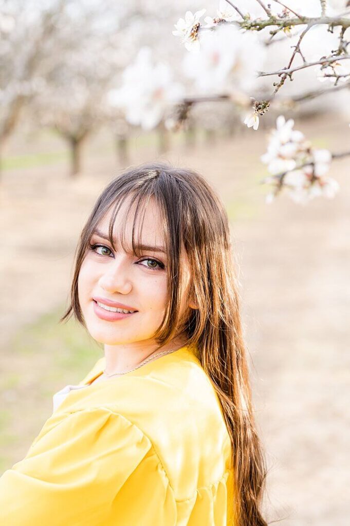 Senior girl smiling at camera pose almond blossom photos in Stockton