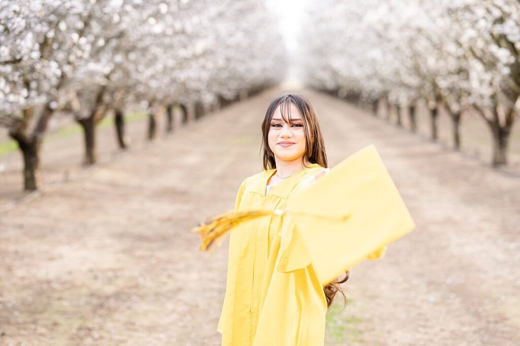 Senior throwing her grad cap during her almond blossom grad session