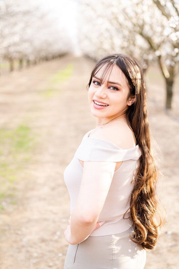 senior girl standing pose idea, looking over her shoulder and smiling