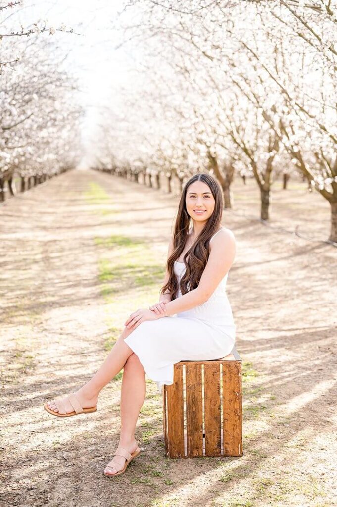 senior girl seated posing idea for almond blossom grad session