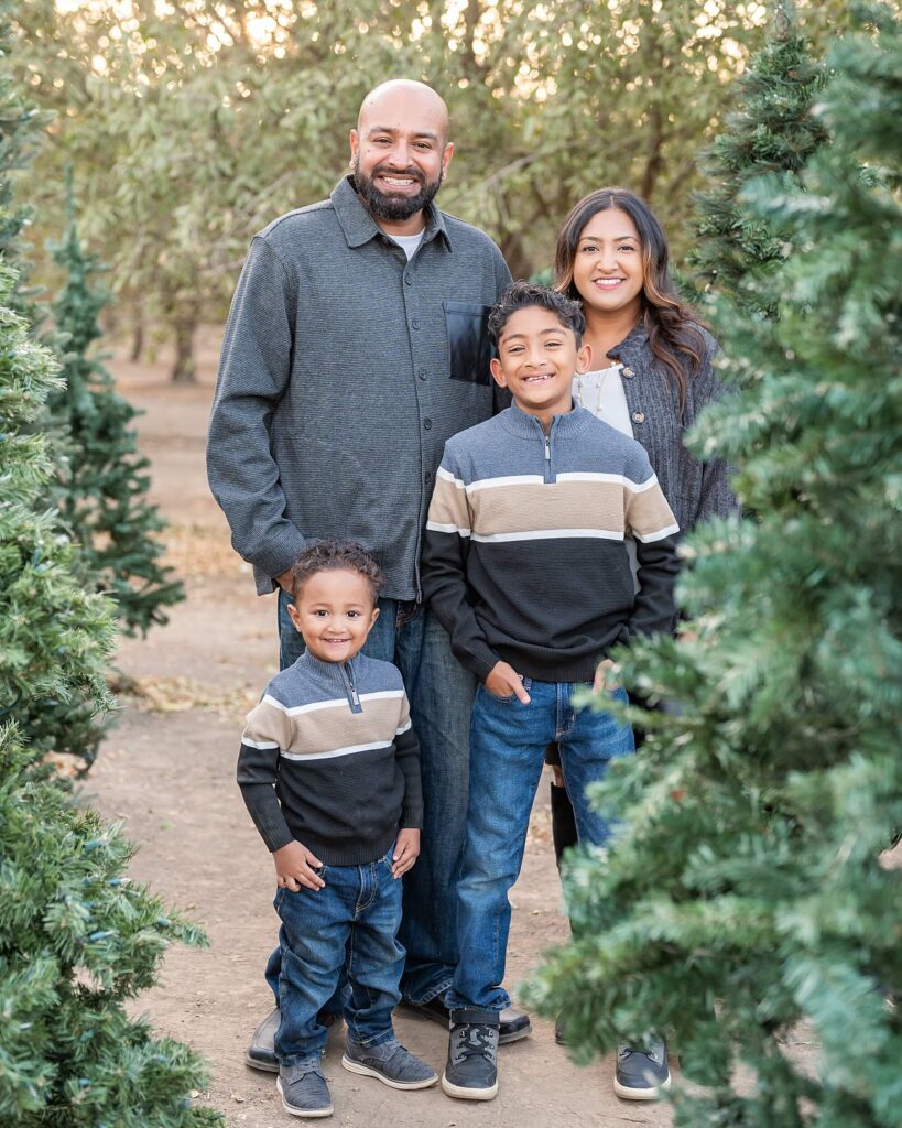 Family smiling together among Christmas trees at Golden R Ranch, Stockton CA, cozy holiday family photo.