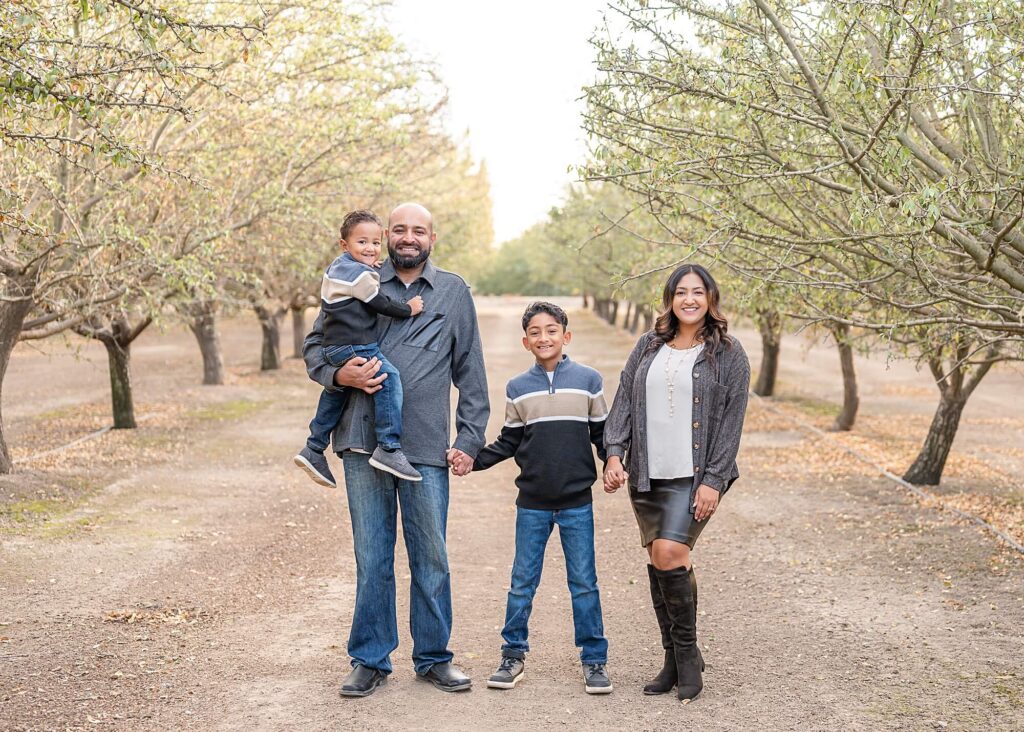 Family smiling together among Almond trees at Golden R, Stockton CA, cute holiday family photo.