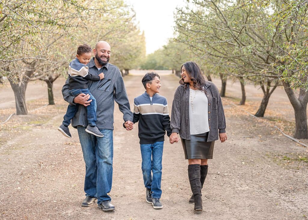 Family walking in an almond farm during their holiday family session in Stockton CA